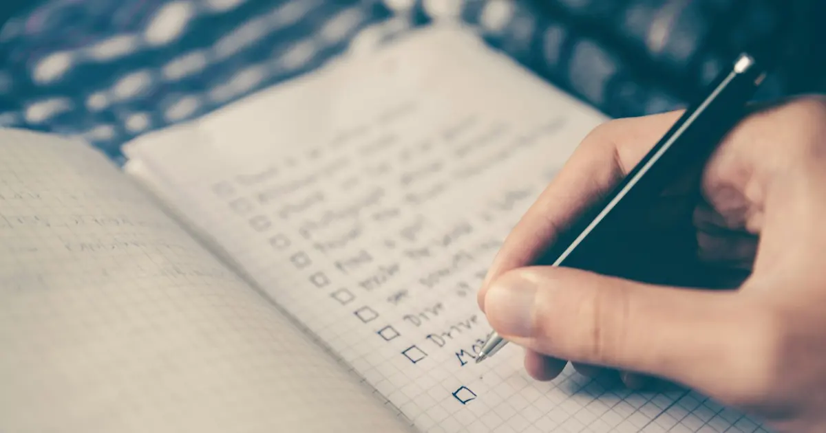 Person writing bucket list on book