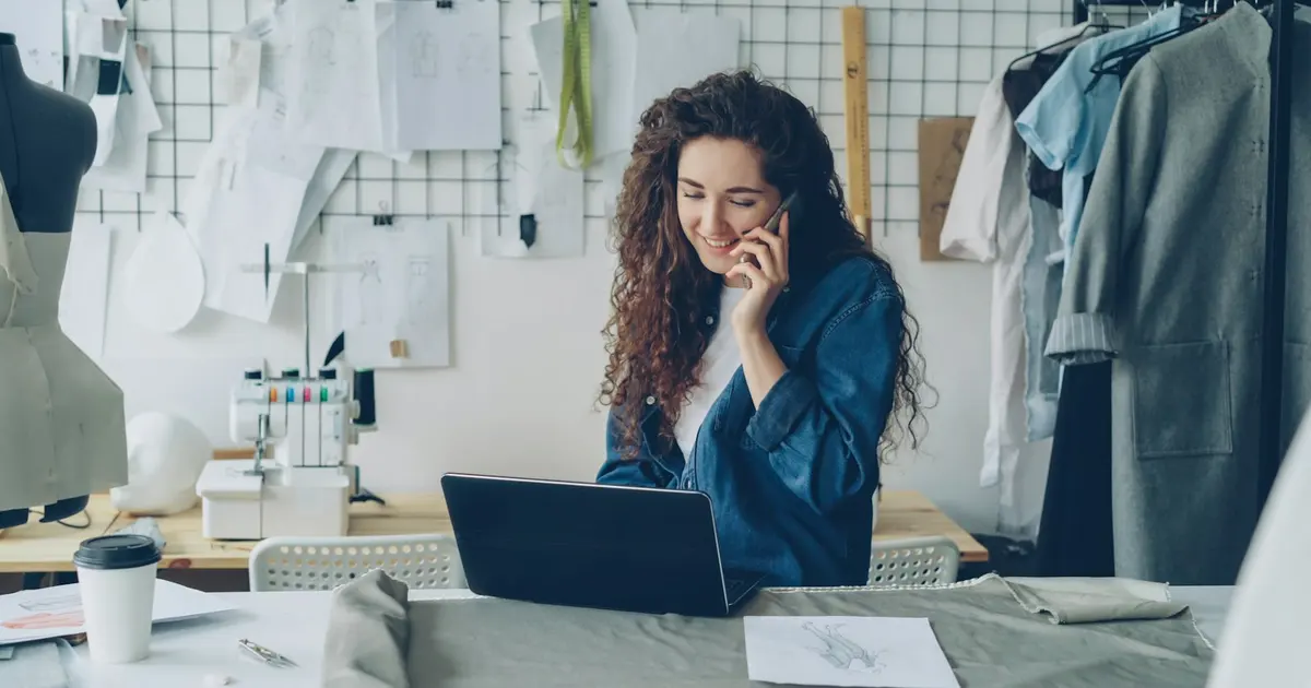 Fashion designer on the phone, working on a laptop